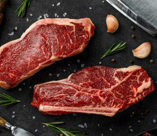 추석 앞두고 한우 할인·사료값 인하로 수급 안정 도모 two steaks on a cutting board next to garlic, garlic, and a knife