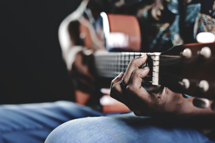 Photo by Ahmed Rizkhaan person playing a brown guitar