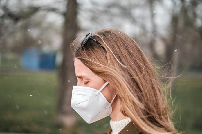 Photo by Jan Baborák a woman wearing a face mask in a park
