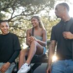 “움직이는 직장인, 건강이 따라온다”… 유연한 근무와 셀프케어 습관이 화제 Three friends talking outdoors on a sunny day.