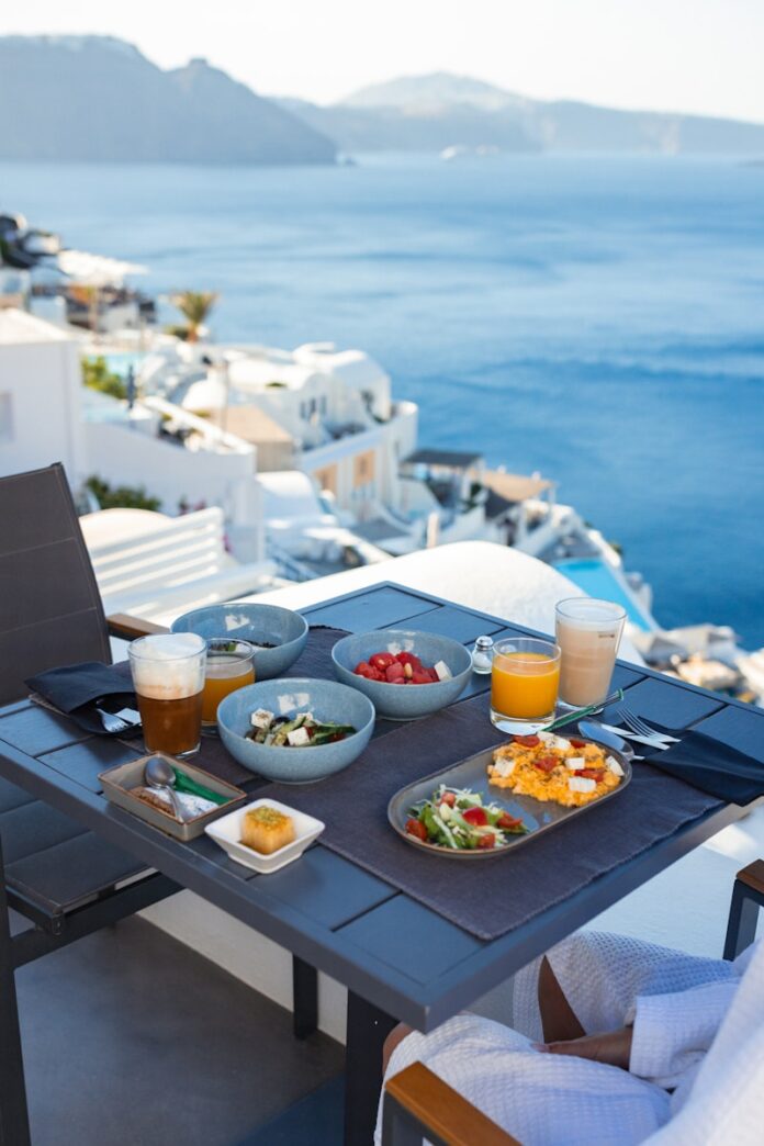 Breakfast on a balcony overlooking the sea and white buildings.